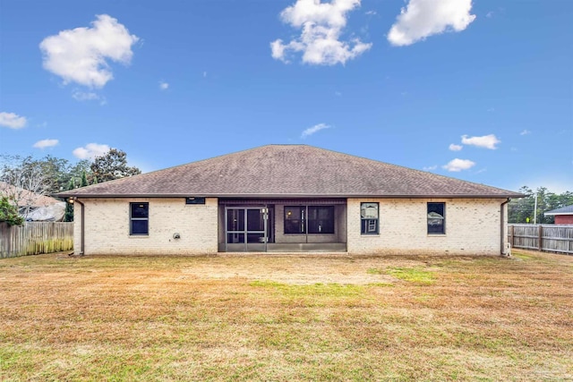 rear view of property featuring a lawn and a sunroom