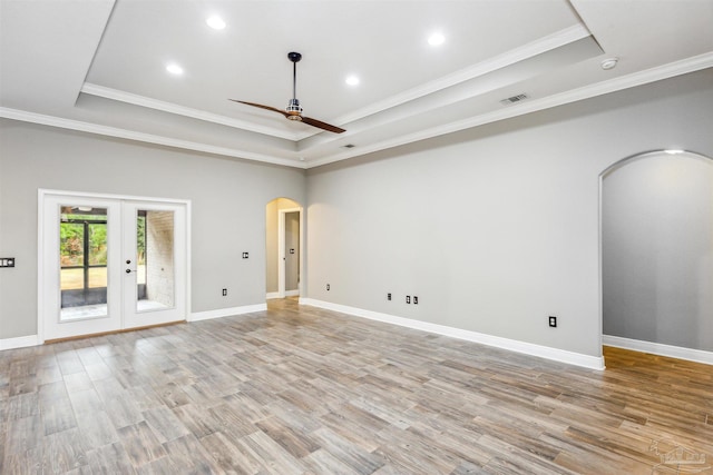 unfurnished room featuring french doors, ornamental molding, a tray ceiling, ceiling fan, and light hardwood / wood-style flooring