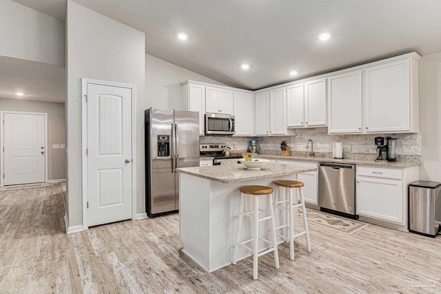 kitchen featuring appliances with stainless steel finishes, light wood-type flooring, and tasteful backsplash