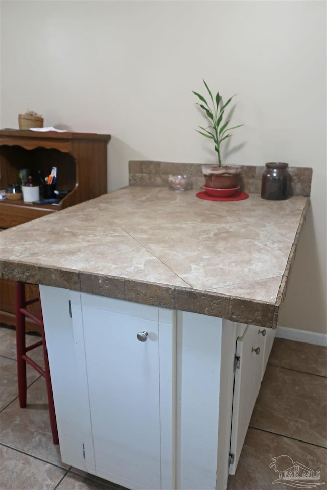 6150 Forest Pines Dr, Pensacola, FL 32526 - kitchen featuring white cabinets, tile patterned flooring, a breakfast bar, a peninsula, and baseboards