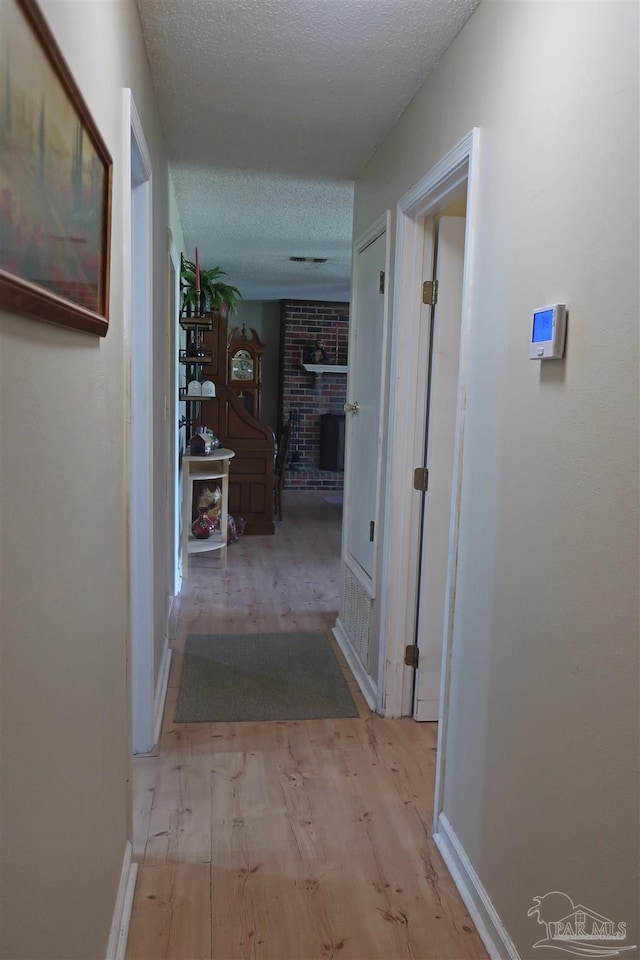 6150 Forest Pines Dr, Pensacola, FL 32526 - hall featuring light wood-type flooring, a textured ceiling, and baseboards