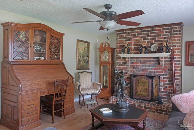 6150 Forest Pines Dr, Pensacola, FL 32526 - living area featuring light wood-style floors, a ceiling fan, a textured ceiling, a fireplace, and a desk