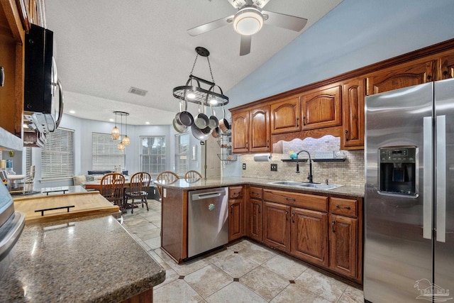 kitchen with pendant lighting, appliances with stainless steel finishes, tasteful backsplash, sink, and kitchen peninsula