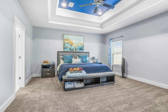 carpeted bedroom with ceiling fan and a tray ceiling