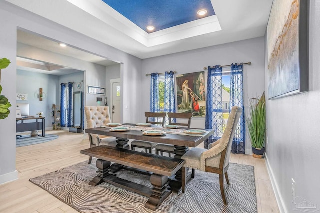 dining area featuring light hardwood / wood-style flooring and a tray ceiling