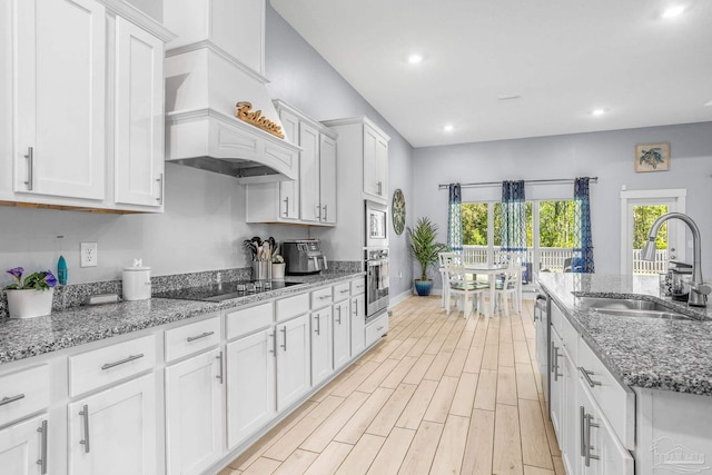 kitchen with stone counters, sink, white cabinets, custom exhaust hood, and stainless steel appliances