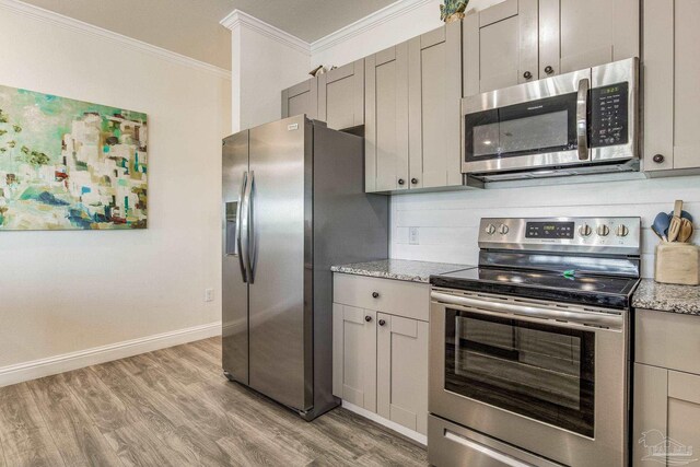 17290 Perdido Key Dr Unit A1, Pensacola, FL 32507 - kitchen with light stone counters, ornamental molding, light wood-style floors, baseboards, and appliances with stainless steel finishes