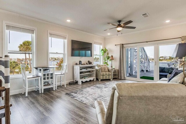 living room with a wealth of natural light, dark wood-type flooring, and crown molding