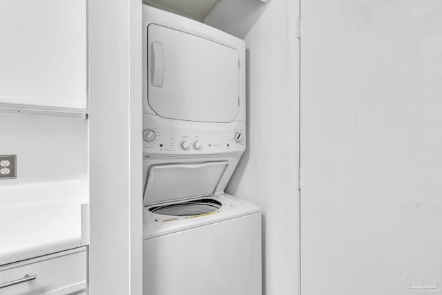 clothes washing area featuring stacked washer / drying machine and laundry area
