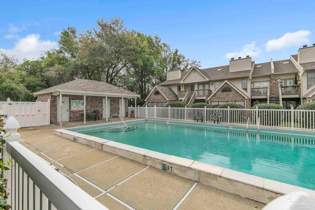 pool featuring an exterior structure, an outbuilding, fence, and a patio area