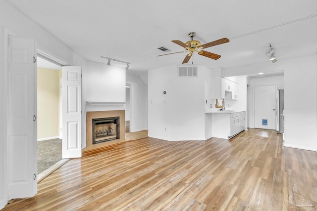 unfurnished living room with visible vents, light wood-style flooring, and ceiling fan