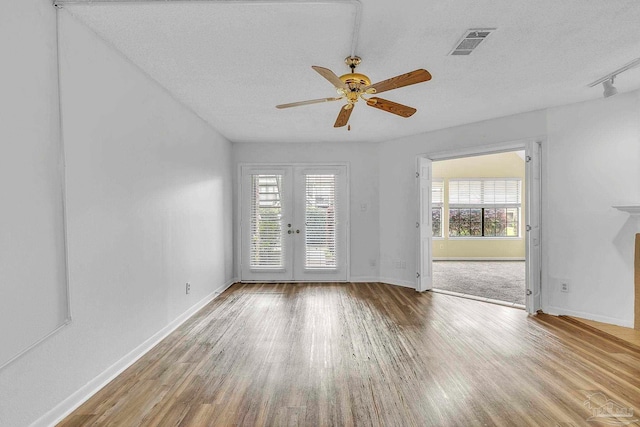 unfurnished living room with visible vents, ceiling fan, wood finished floors, and french doors