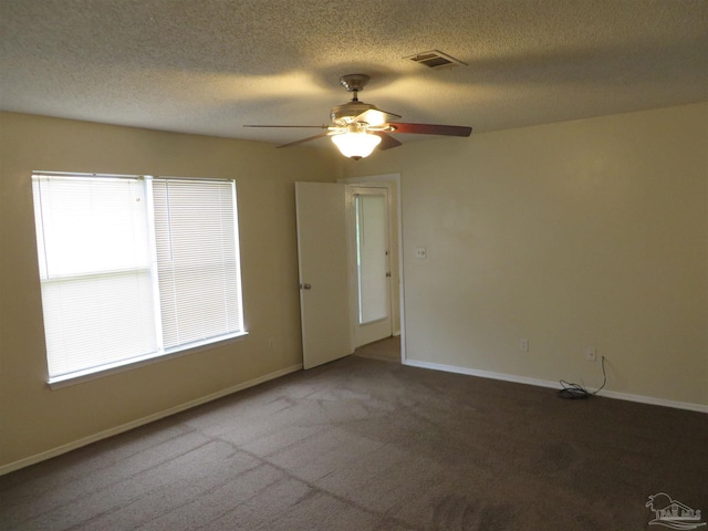 carpeted empty room featuring a textured ceiling, ceiling fan, baseboards, and visible vents