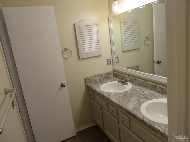 bathroom featuring double vanity, a sink, and baseboards