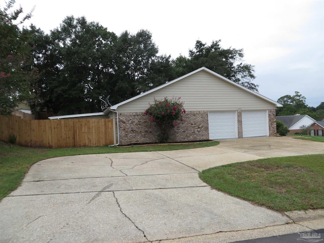 exterior space featuring driveway, fence, and brick siding