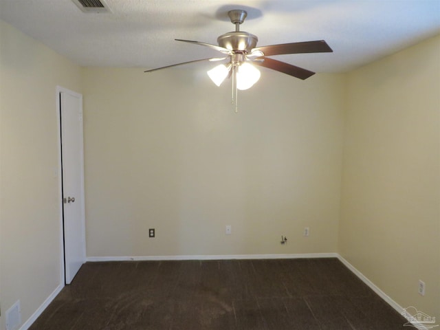 unfurnished room with visible vents, baseboards, dark carpet, and ceiling fan