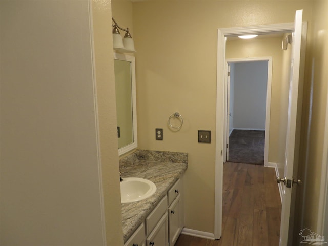 bathroom featuring vanity, baseboards, and wood finished floors
