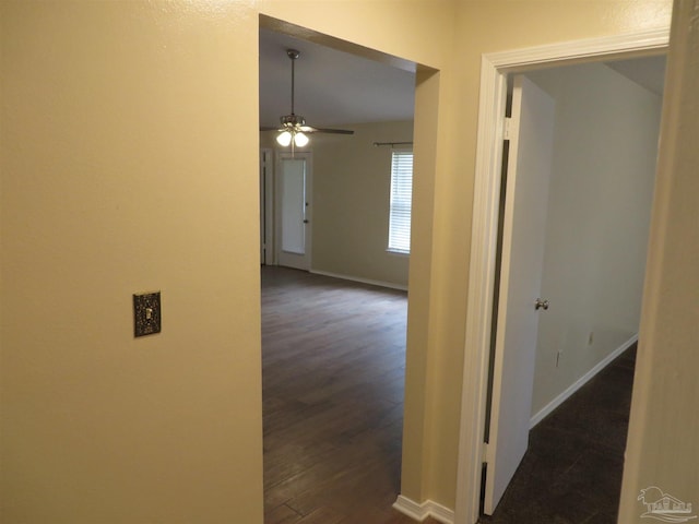 corridor featuring baseboards and dark wood finished floors