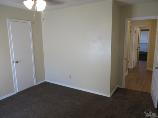 unfurnished room with dark carpet and ceiling fan