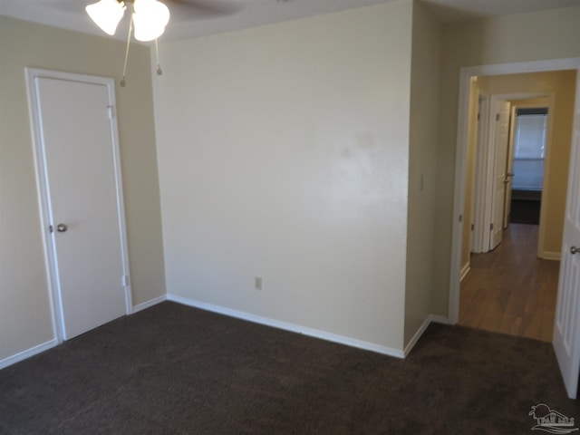 carpeted spare room featuring ceiling fan and baseboards