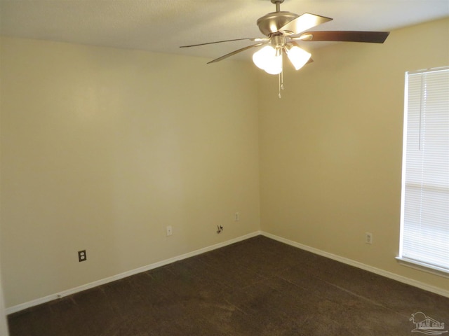 unfurnished room with dark carpet, baseboards, and a ceiling fan