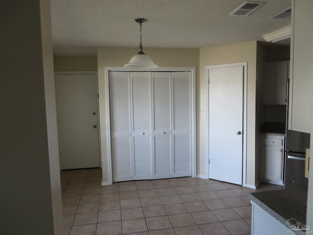 interior space featuring a textured ceiling, light tile patterned floors, and decorative light fixtures