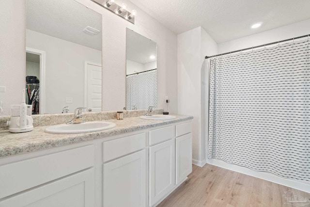 5252 Peach Dr, Pace, FL 32571 - full bathroom with a shower with shower curtain, double vanity, wood finished floors, and a textured ceiling