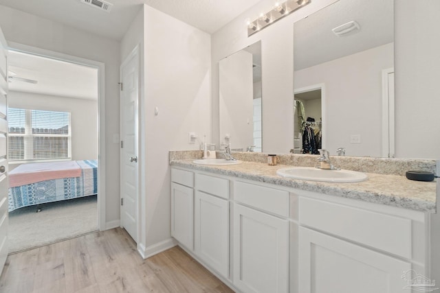 5252 Peach Dr, Pace, FL 32571 - bathroom with double vanity, wood finished floors, ensuite bath, a walk in closet, and baseboards