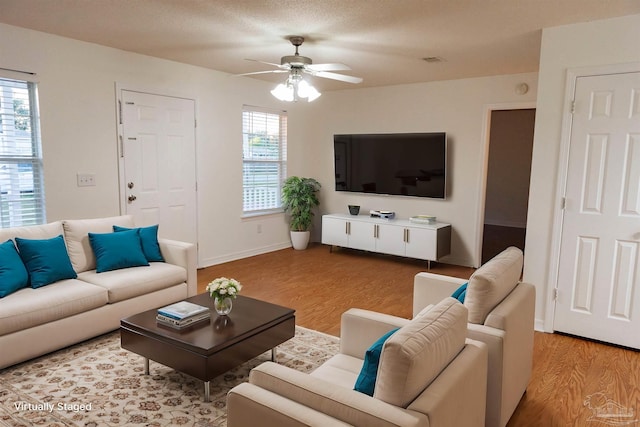 living room featuring visible vents, a ceiling fan, baseboards, and wood finished floors