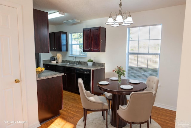 kitchen featuring black dishwasher, a chandelier, a sink, light wood-style flooring, and hanging light fixtures