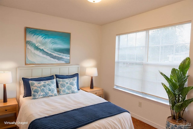 bedroom featuring baseboards, multiple windows, and wood finished floors
