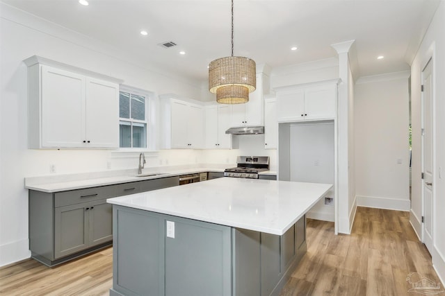 kitchen with a sink, a kitchen island, visible vents, light countertops, and appliances with stainless steel finishes