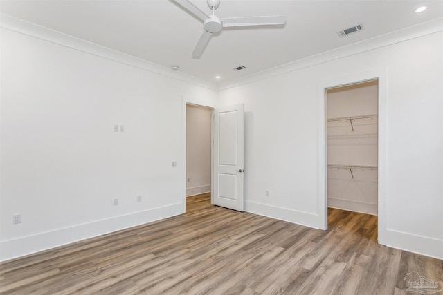 unfurnished bedroom with baseboards, crown molding, visible vents, and wood finished floors