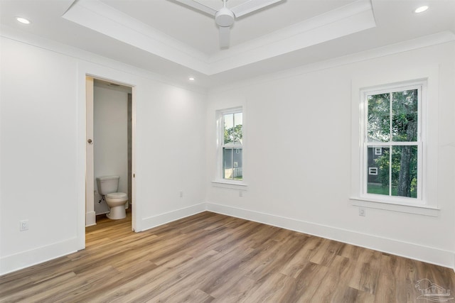 unfurnished room with baseboards, ornamental molding, wood finished floors, a tray ceiling, and recessed lighting