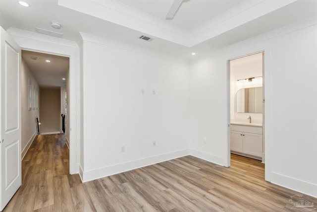 unfurnished bedroom featuring light wood finished floors, a sink, visible vents, and baseboards