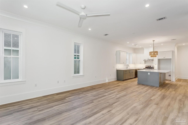 kitchen featuring visible vents, white cabinetry, light countertops, hanging light fixtures, and a center island