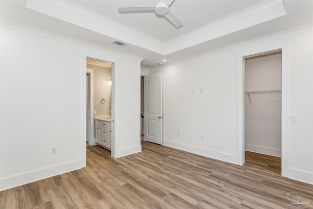 unfurnished bedroom featuring a closet, a raised ceiling, visible vents, and wood finished floors