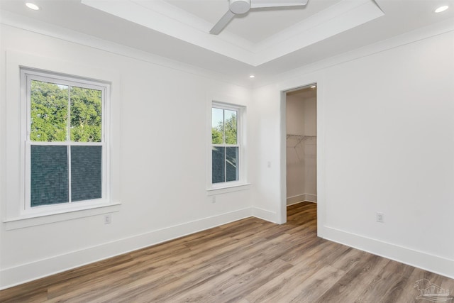 unfurnished bedroom with light wood finished floors, a tray ceiling, recessed lighting, and baseboards