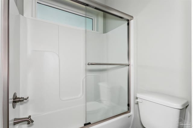 bathroom featuring toilet and combined bath / shower with glass door