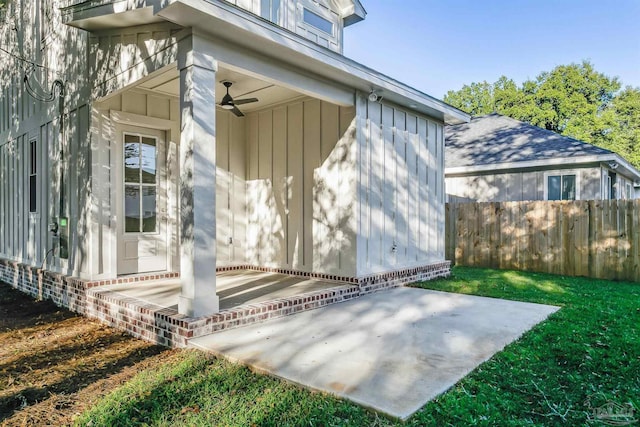 entrance to property featuring a patio area, ceiling fan, fence, and a lawn