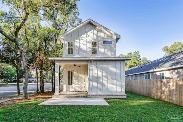 back of property with a patio, an outdoor structure, fence, a lawn, and board and batten siding