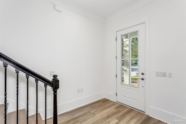 entryway featuring light wood-style floors, crown molding, stairway, and baseboards