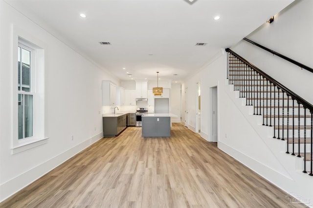 kitchen featuring a kitchen island, white cabinets, stainless steel range oven, light countertops, and pendant lighting