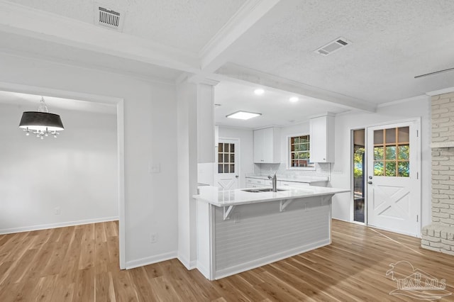 kitchen featuring white cabinets, beamed ceiling, light hardwood / wood-style floors, and a breakfast bar