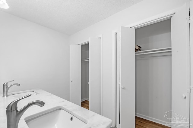 washroom featuring sink, a textured ceiling, and dark hardwood / wood-style flooring