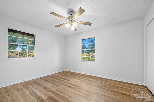 empty room with ceiling fan, a textured ceiling, and light wood-type flooring