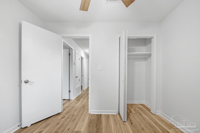 unfurnished bedroom with ceiling fan, a textured ceiling, a closet, and light hardwood / wood-style flooring