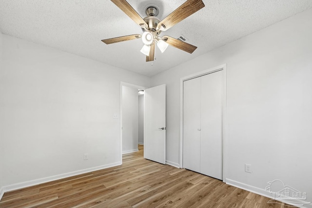 unfurnished bedroom with ceiling fan, a textured ceiling, a closet, and light hardwood / wood-style flooring