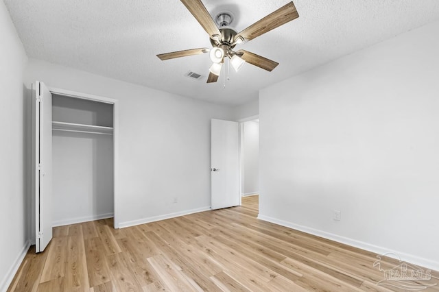 unfurnished bedroom featuring light wood-type flooring, a textured ceiling, a closet, and ceiling fan