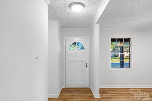 foyer entrance with a wealth of natural light, ornamental molding, a textured ceiling, and wood-type flooring